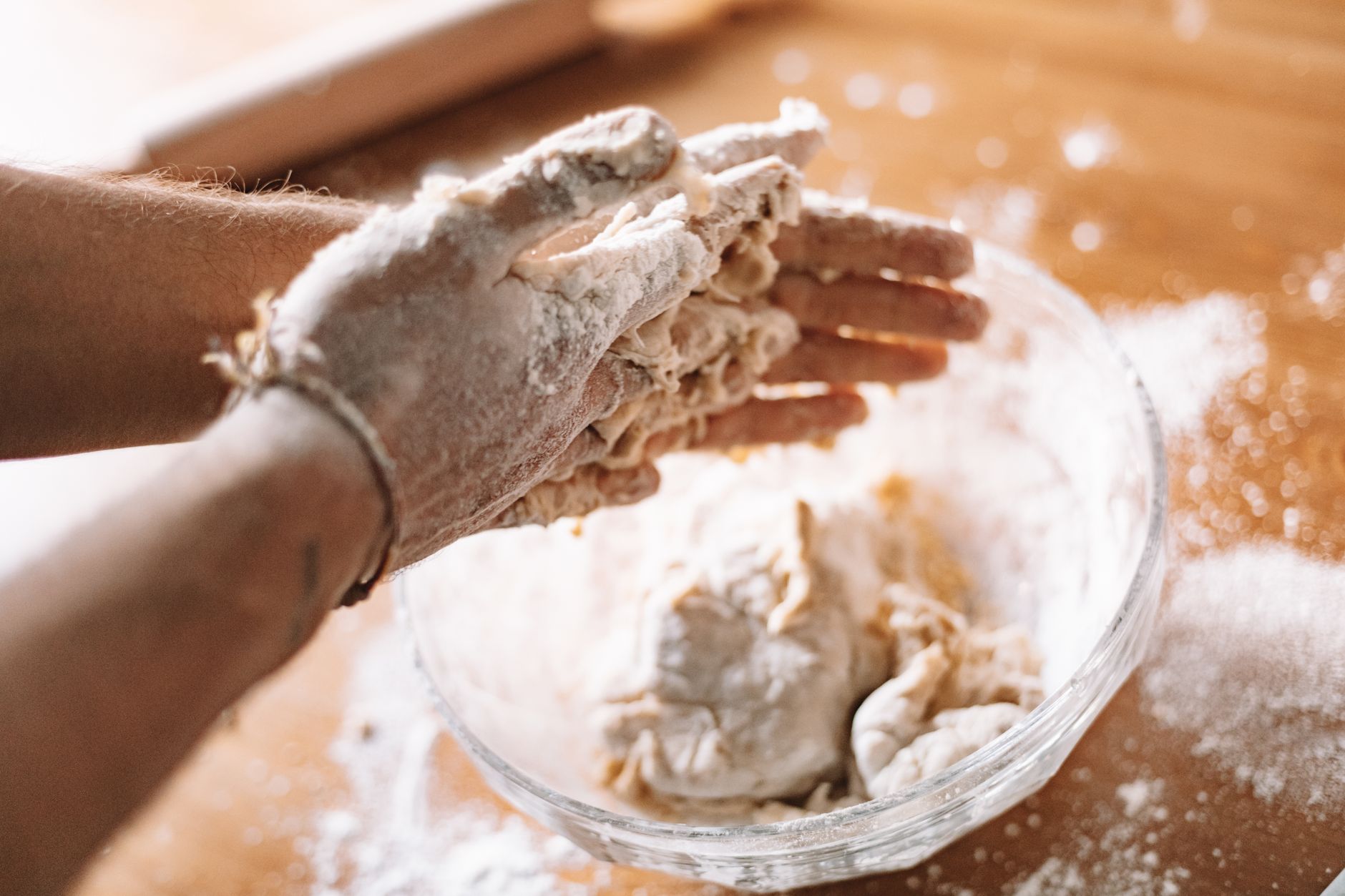 Close-up of hands kneading dough in a kitchen, showcasing food preparation.