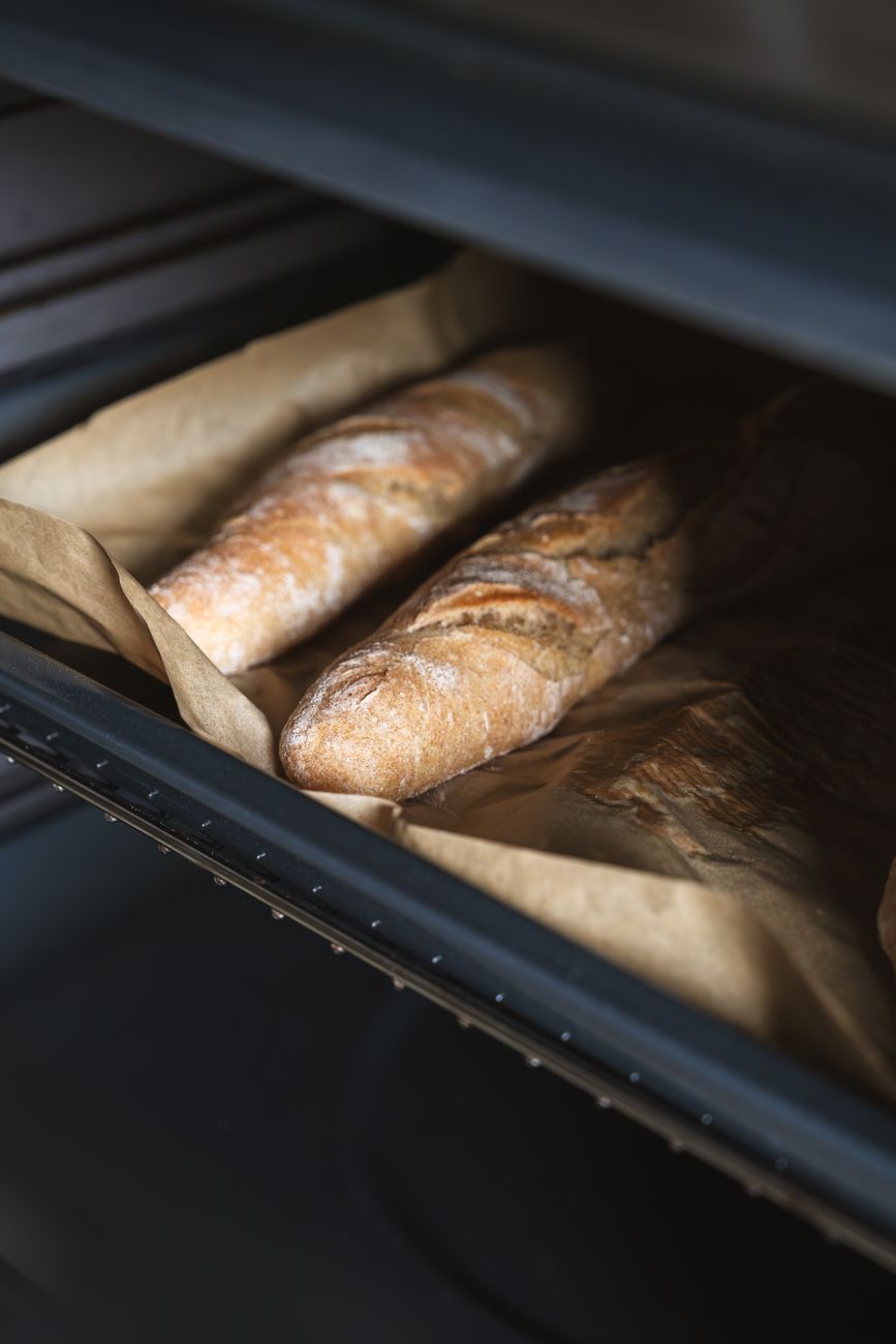 Close-up of freshly baked baguettes in an oven showcasing artisanal bakery techniques.