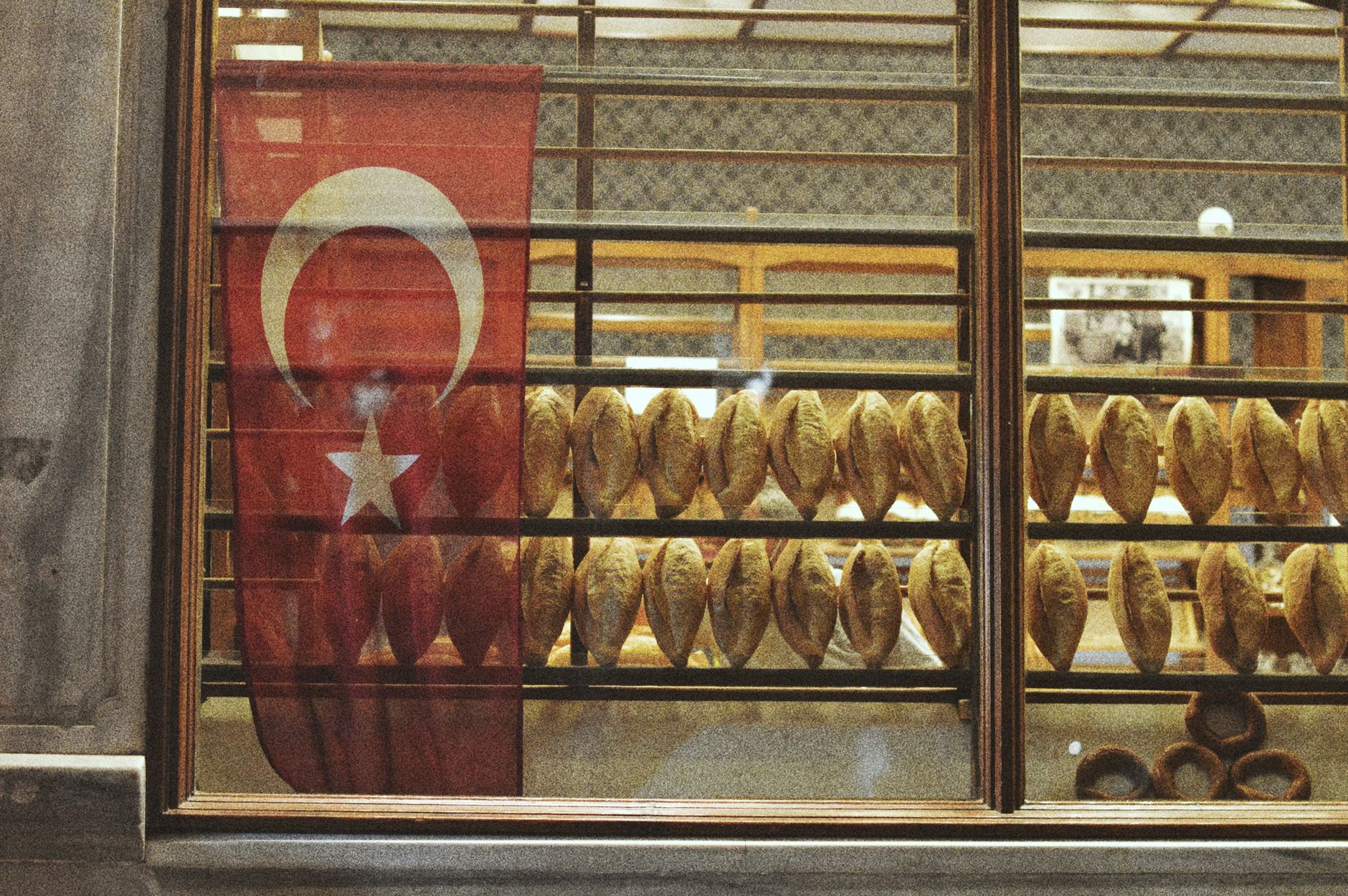 A Turkish bakery window showcasing fresh bread and a Turkish flag, creating a warm ambiance.